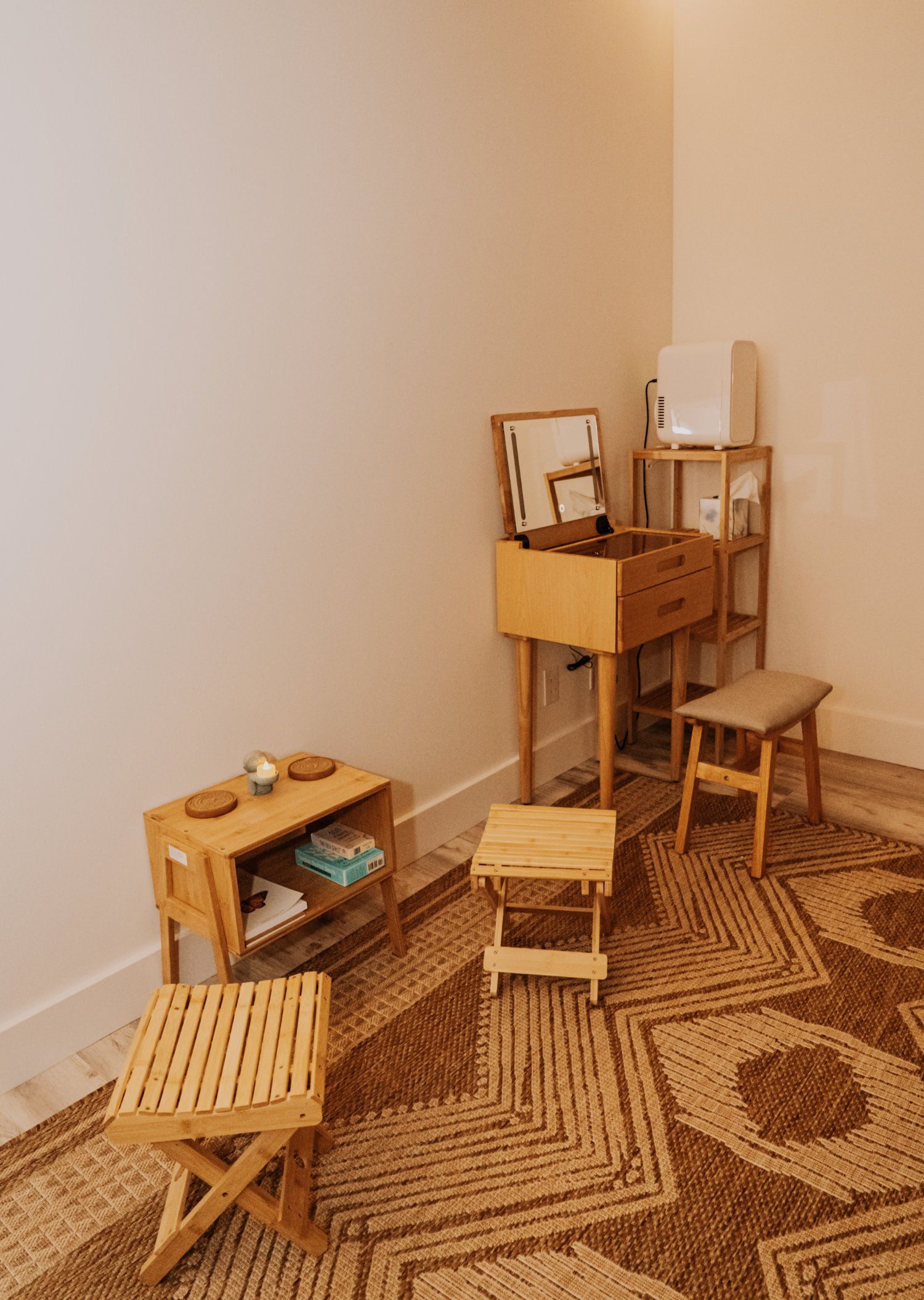 Wooden furniture corner: stools, shelves, boxes, rug. Neutral colors.