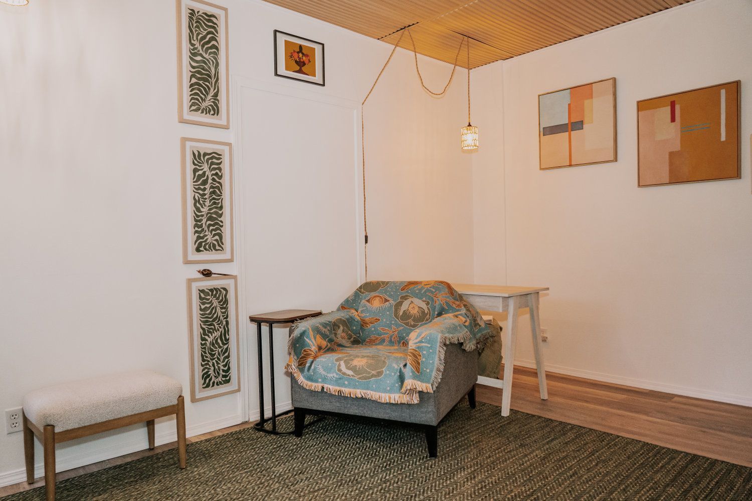 Cozy reading nook with armchair, artwork, and hanging light.
