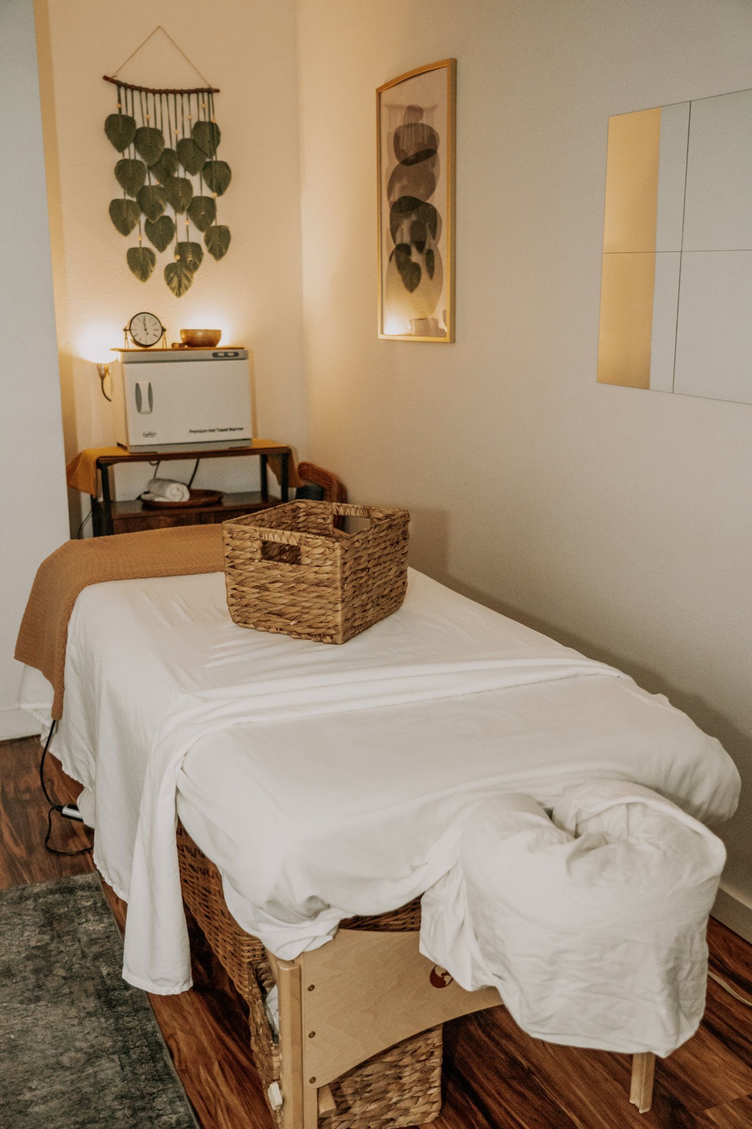 Massage room with a massage table, woven basket, and wall art.