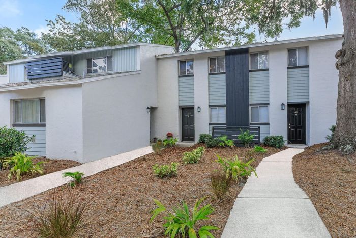 Townhouse exterior with pathway, landscaping, light gray and dark blue siding.