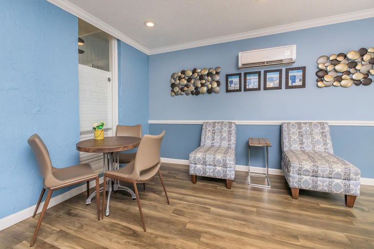 Waiting room with blue walls, patterned chairs, round table, and decorative wall art.