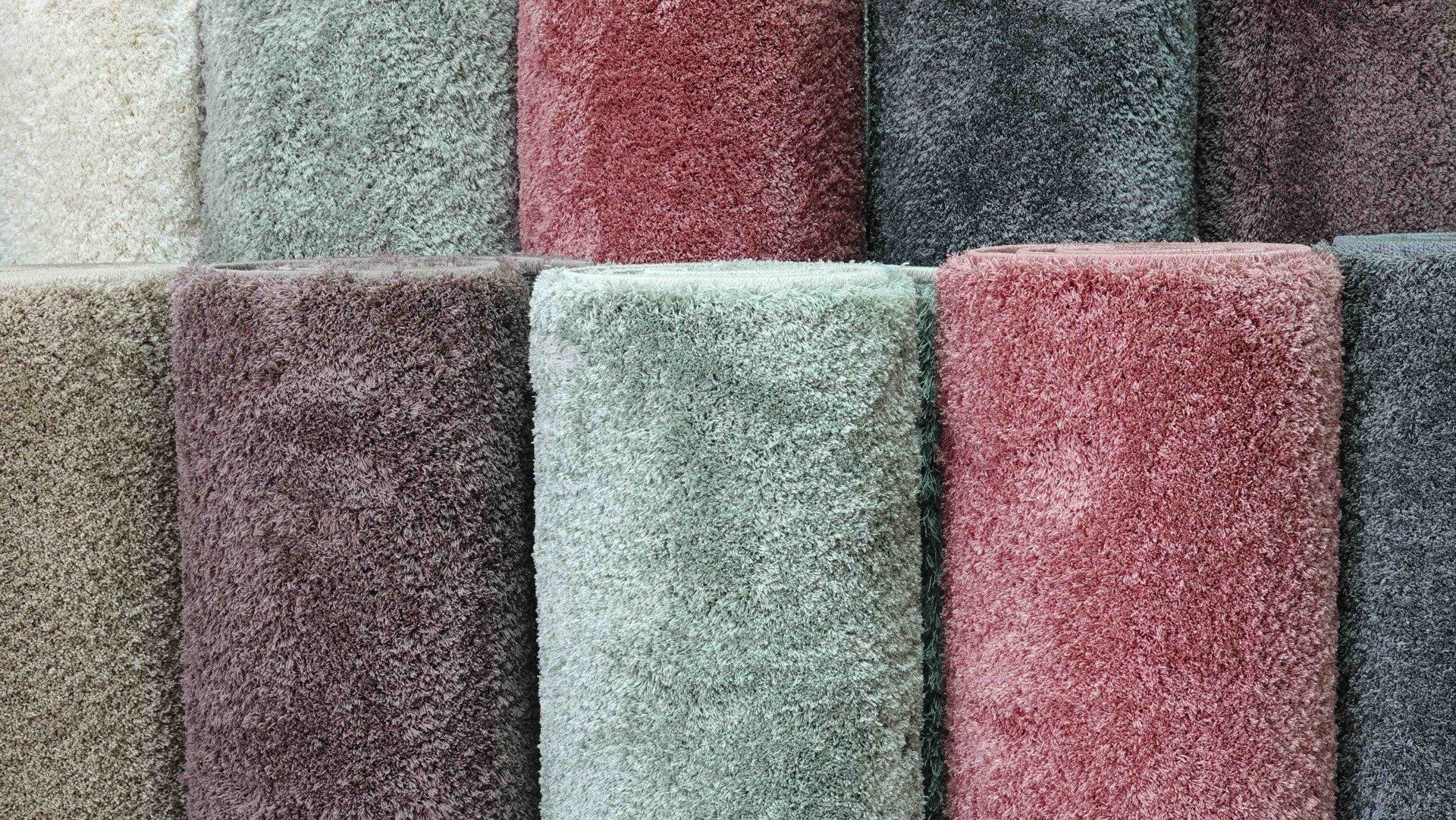 A bunch of different colored carpets are stacked on top of each other.