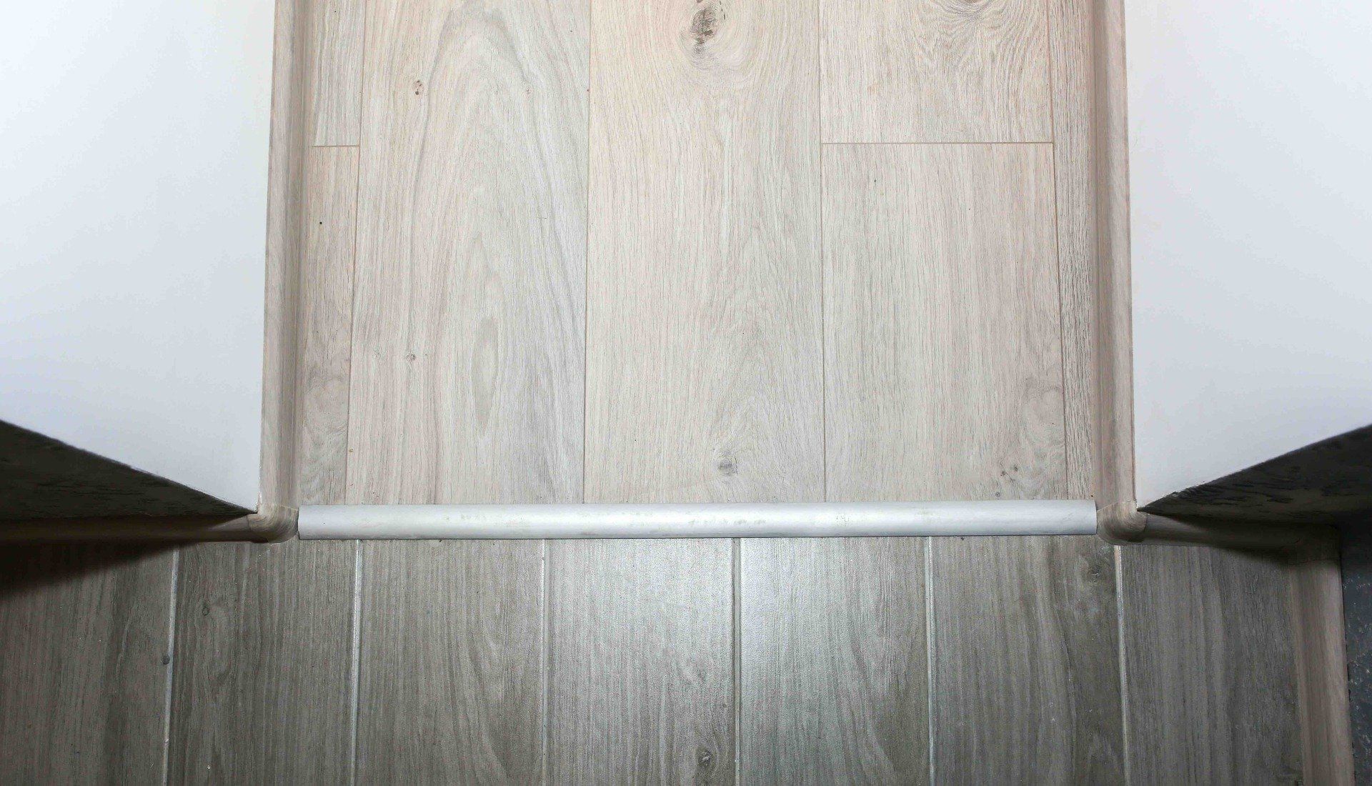 A close up of a wooden floor with a white trim.