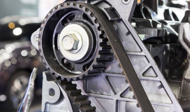 Close-up of a car engine timing belt and gear assembly with metal components.