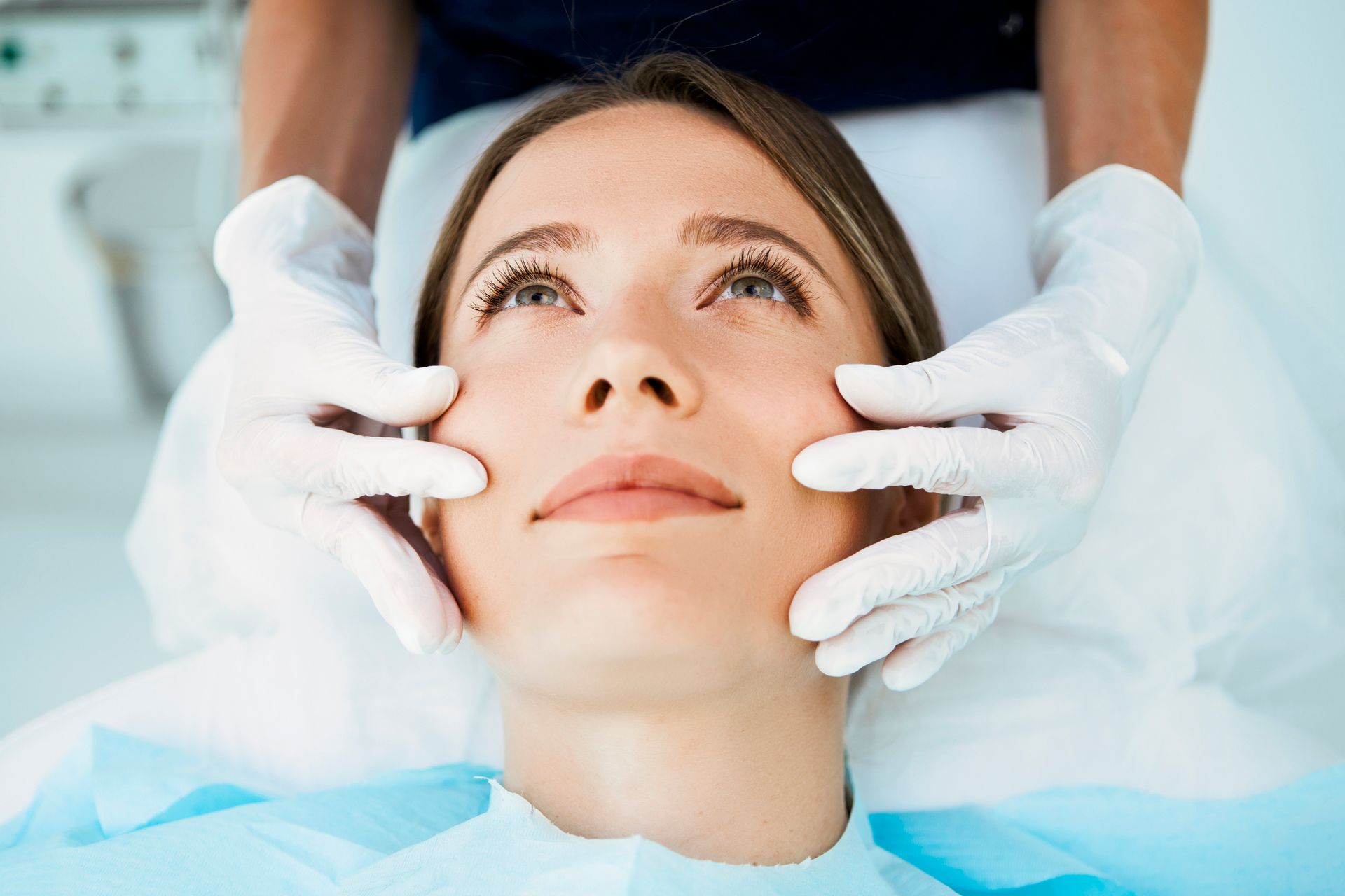 A woman is getting her face examined by a doctor.