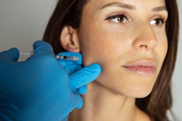 A woman is getting a botox injection in her face.