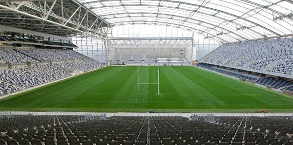 An empty stadium with a green field and a goal.