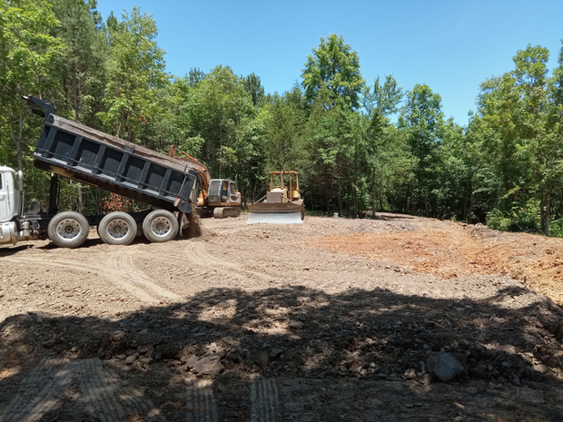 A dump truck is dumping dirt on a construction site.