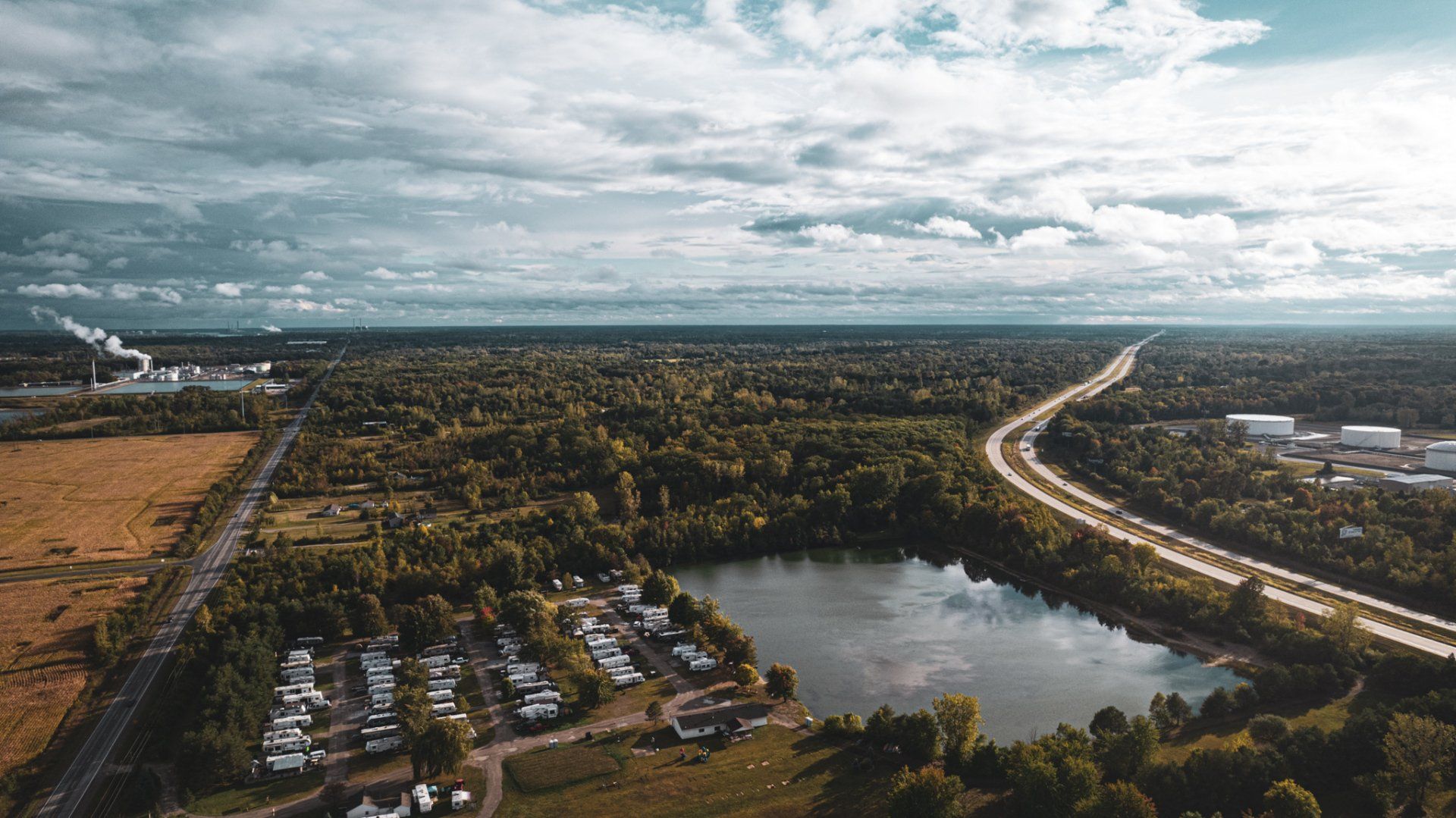 An aerial view of a lake surrounded by trees and a highway.