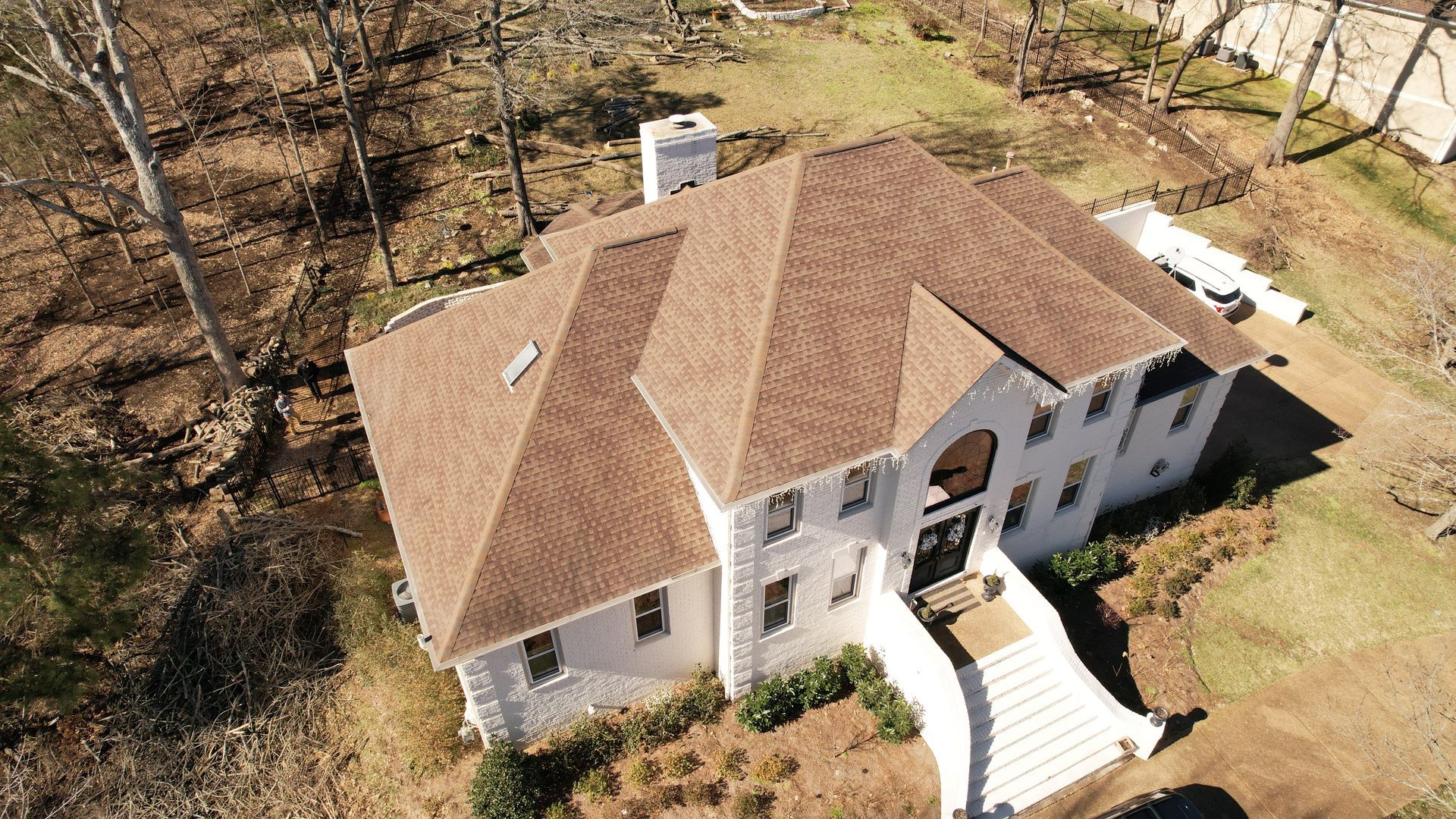 An aerial view of a large white house with a brown roof