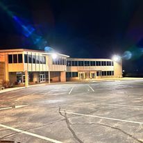 A large building with a parking lot in front of it at night.