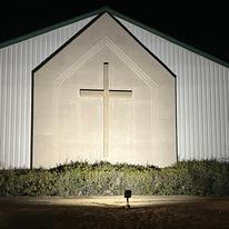 A church with a cross on the side of it at night.