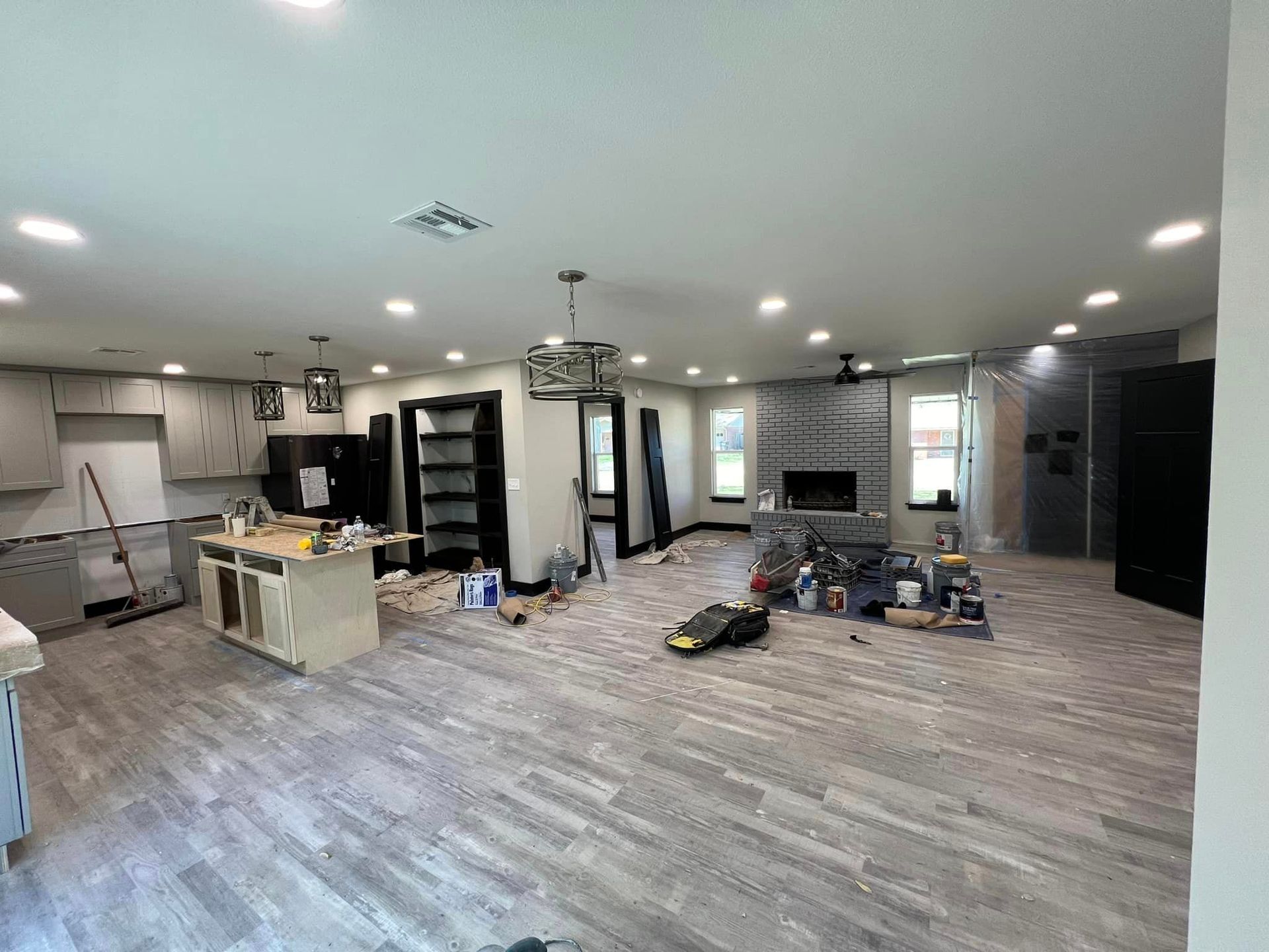 A large living room with hardwood floors and a kitchen in a house under construction.