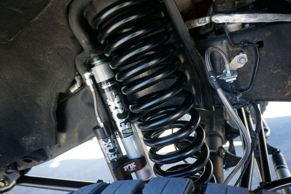 Red coilover shock absorbers with red springs on a black surface, close-up.