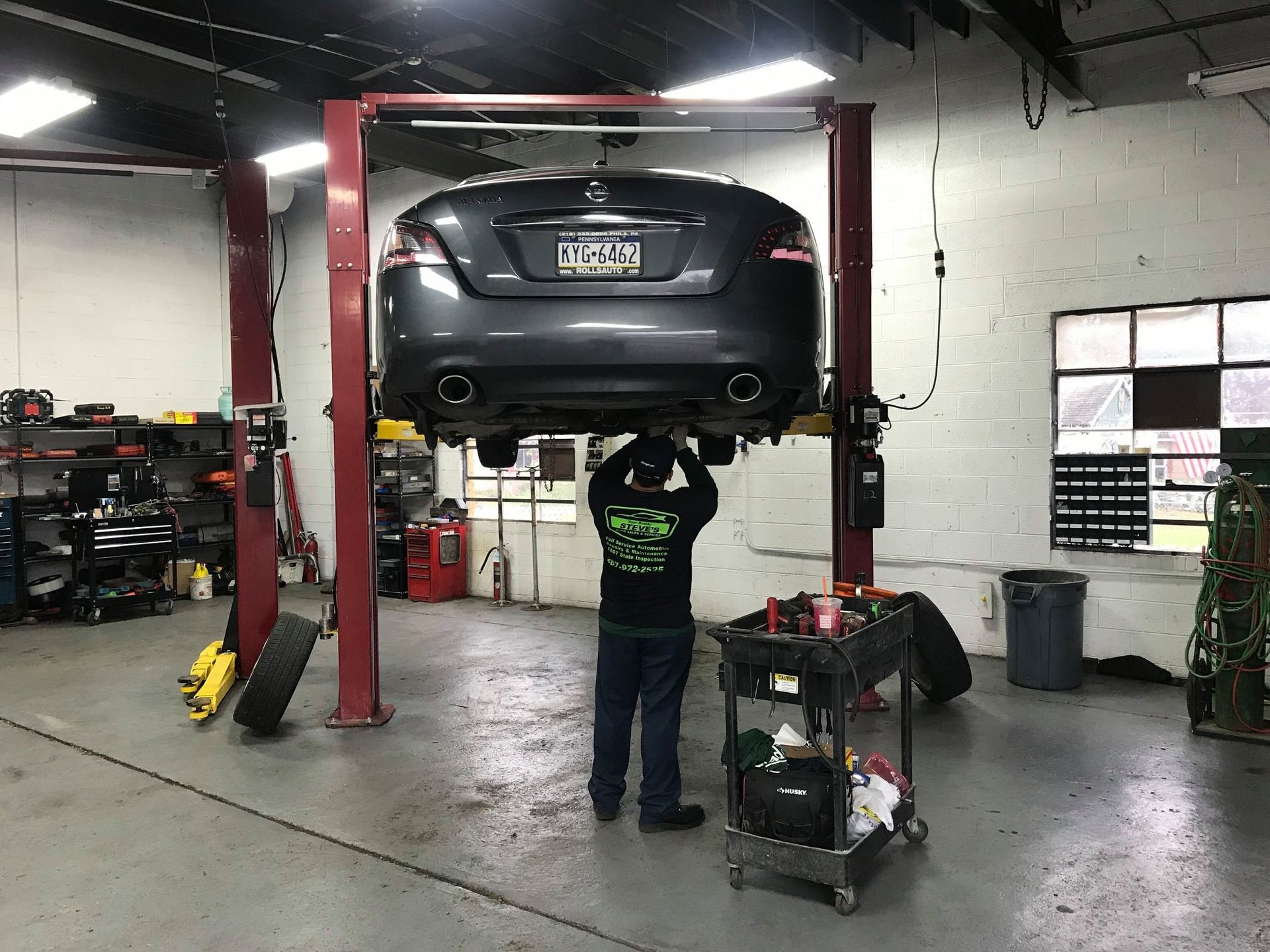 Mechanic working on car raised on a lift inside a garage. | Your Buddy Steve's Garage
