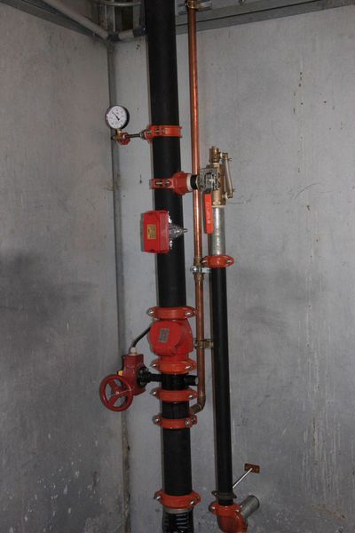 A pipe with a gauge attached to it is in a room.