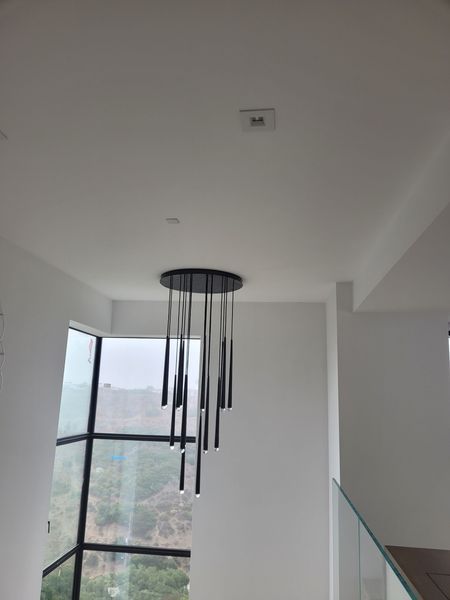 A chandelier is hanging from the ceiling in a room with a large window.