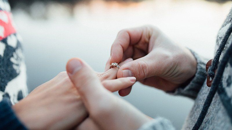 man putting a ring on woman's finger