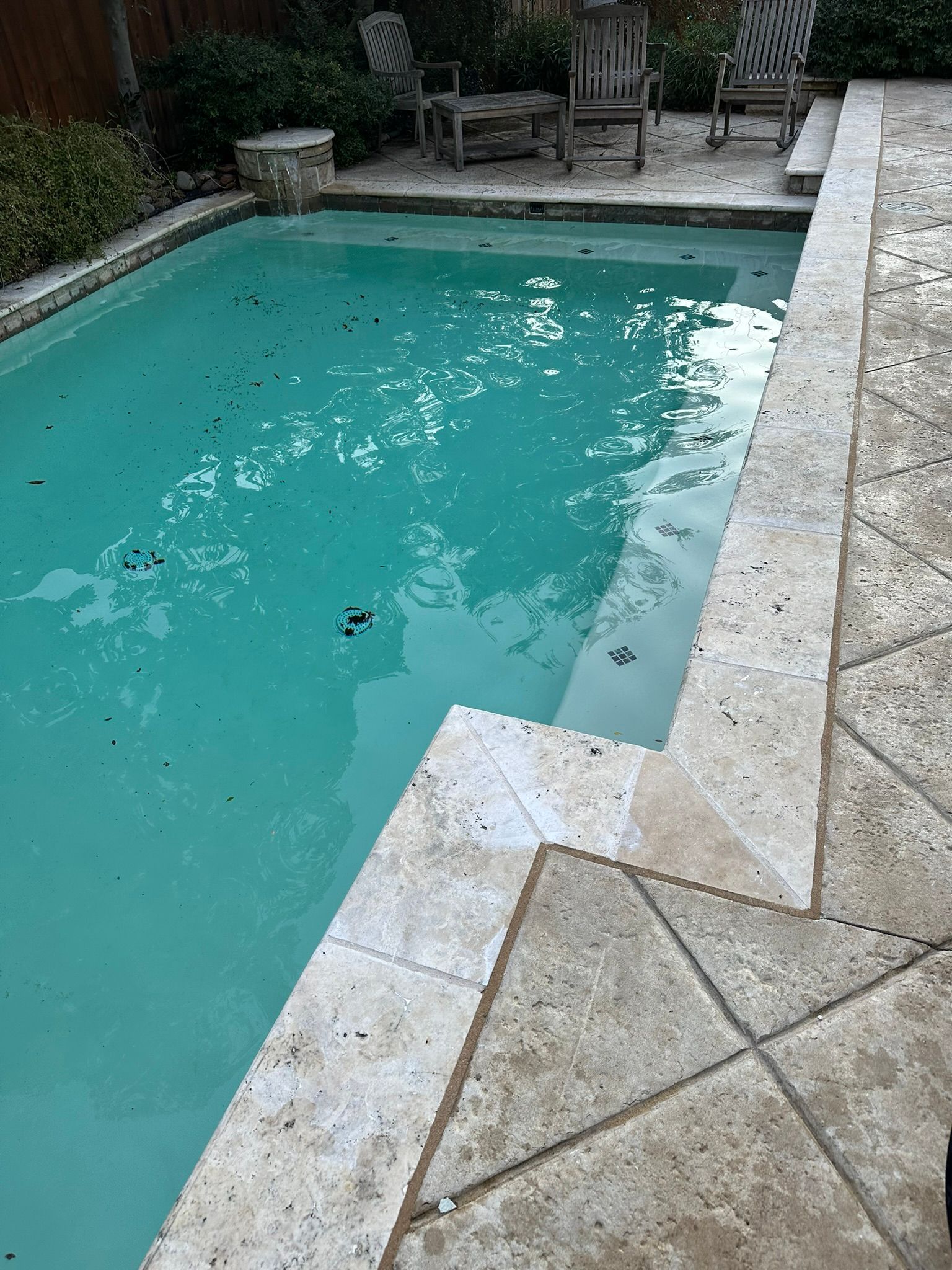 Swimming pool with turquoise water, stone coping, and patio.