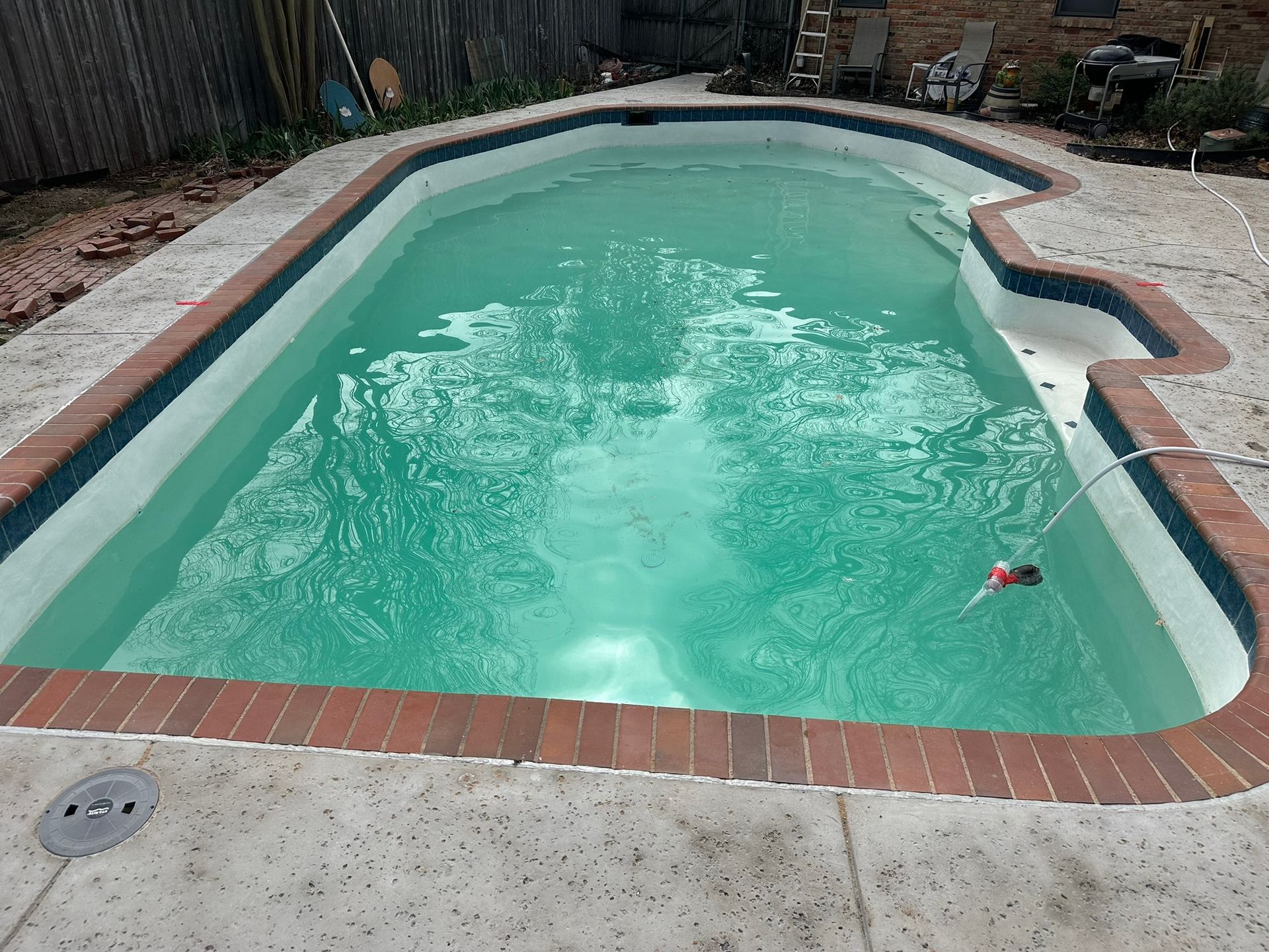 Pool filled with turquoise water, surrounded by red brick and concrete.