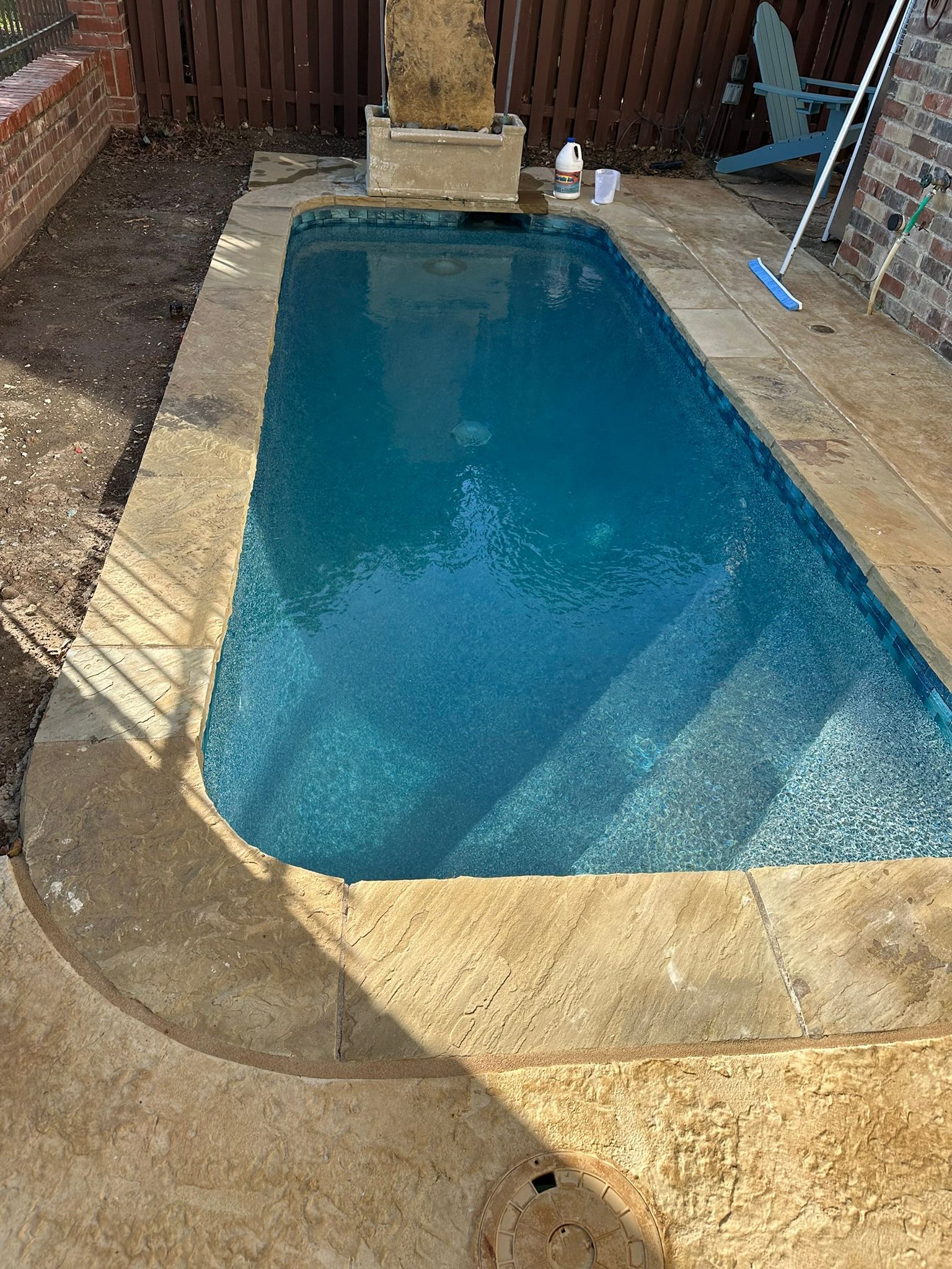 Rectangular pool with blue water and stone surround, outdoors.