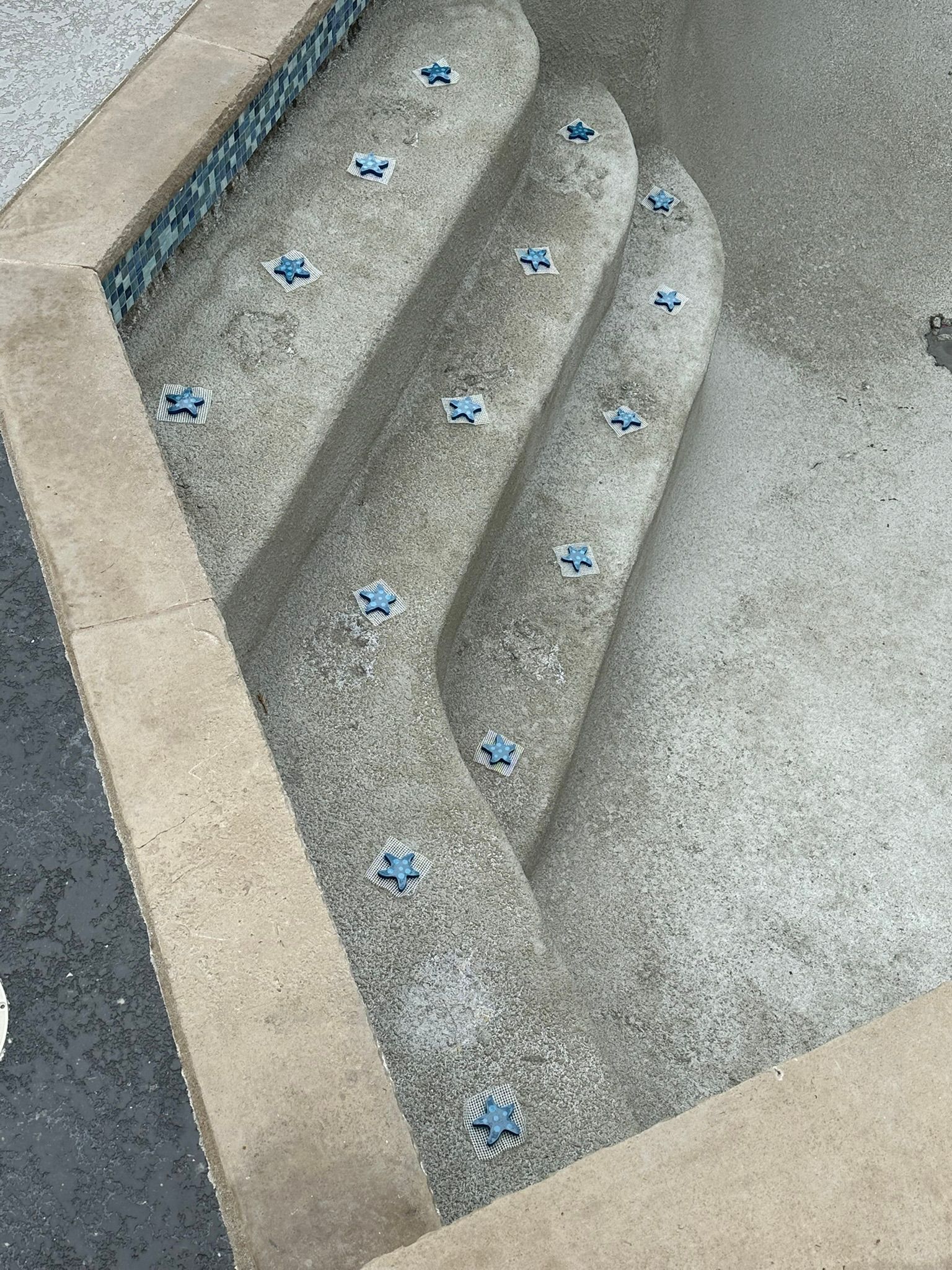 Concrete pool steps with blue tile accents.