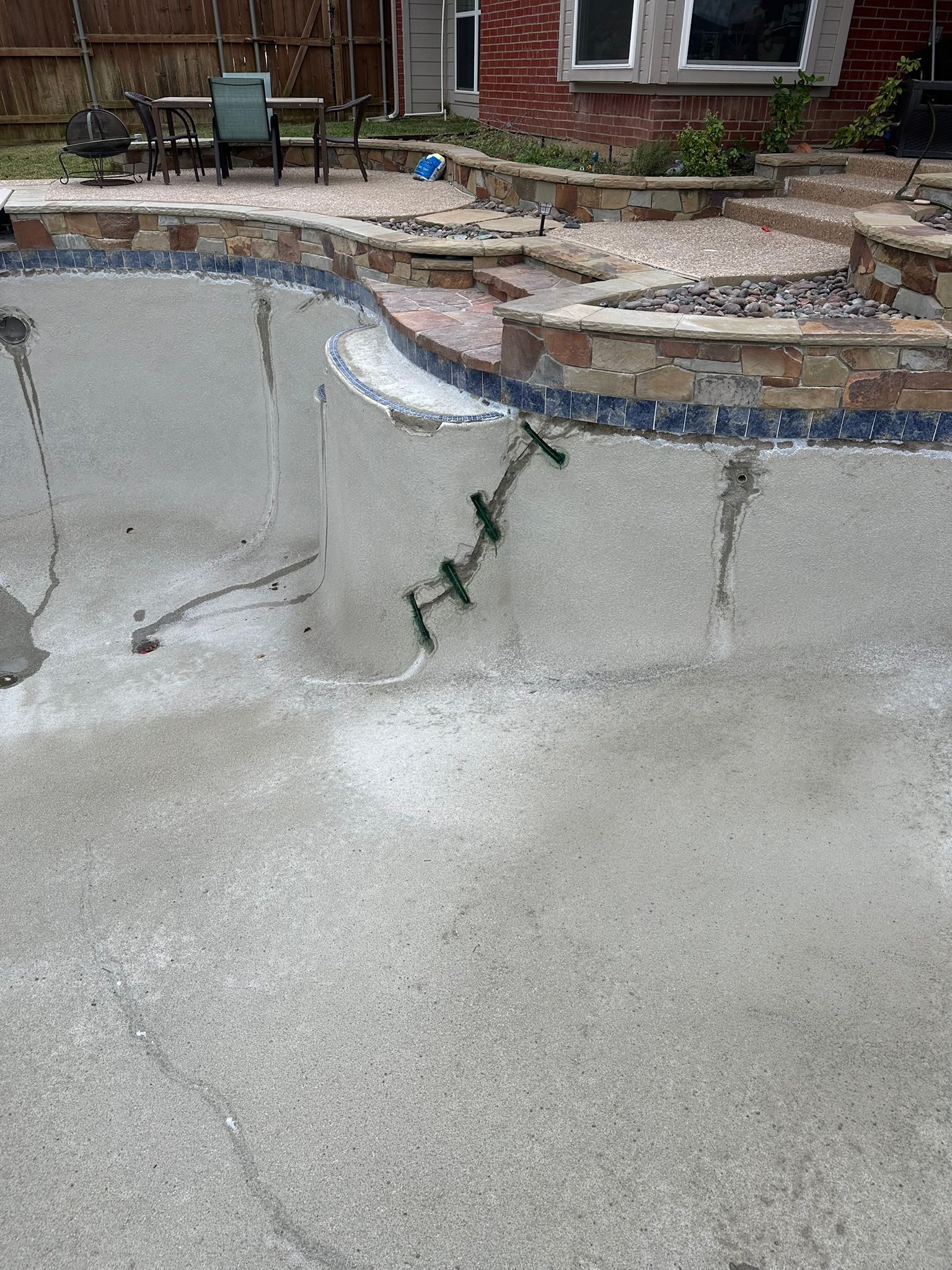 Pool under construction with exposed concrete and a tiled edge.