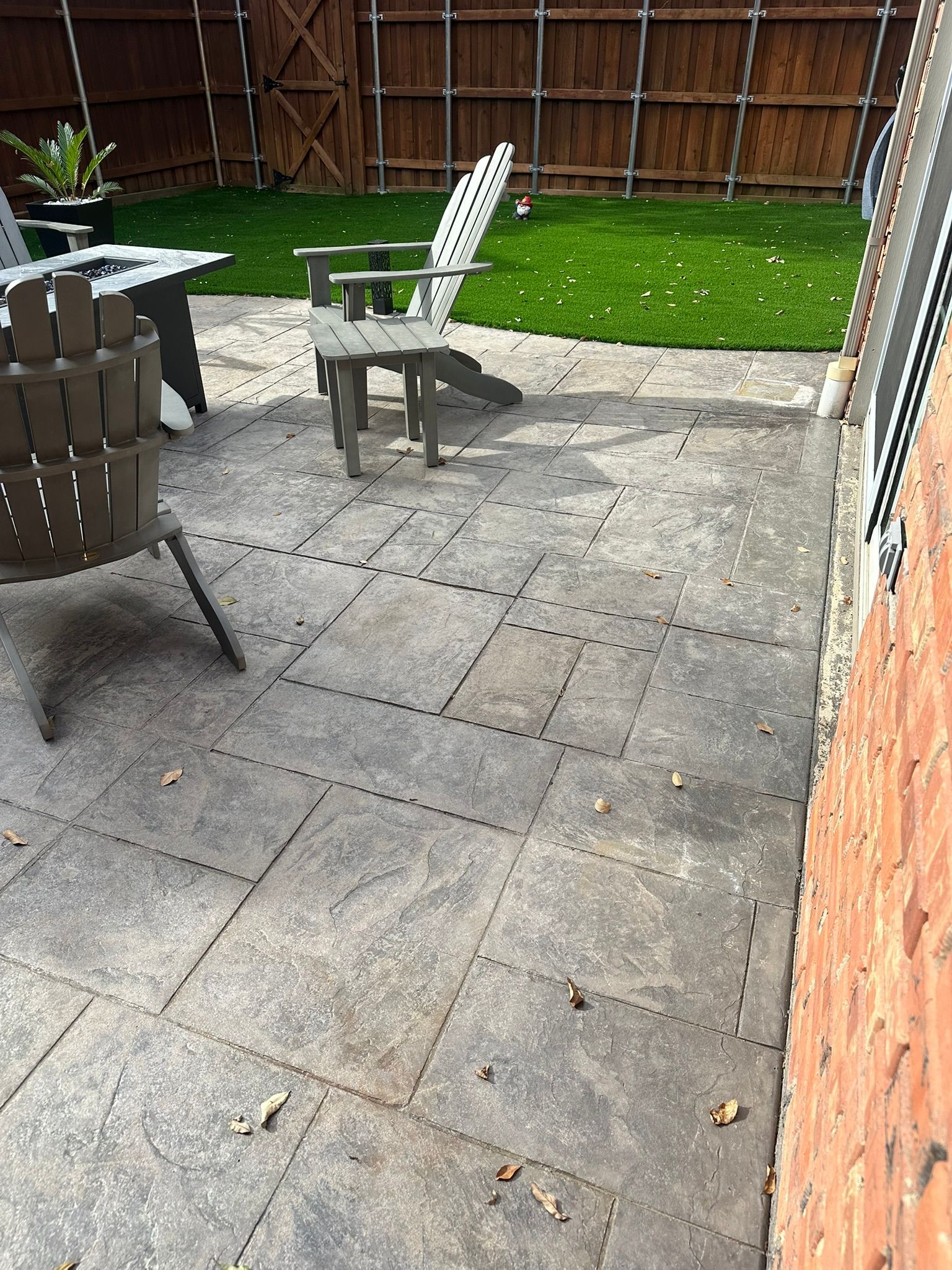 Patio with gray stone pavers, chairs, and a grassy backyard.