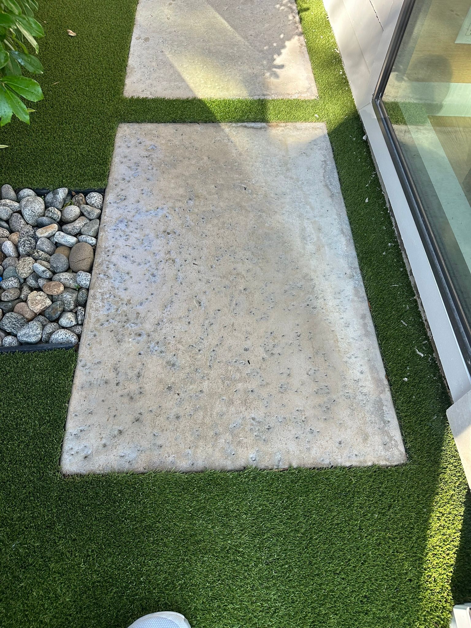 Concrete pathway stepping stones in green artificial turf.
