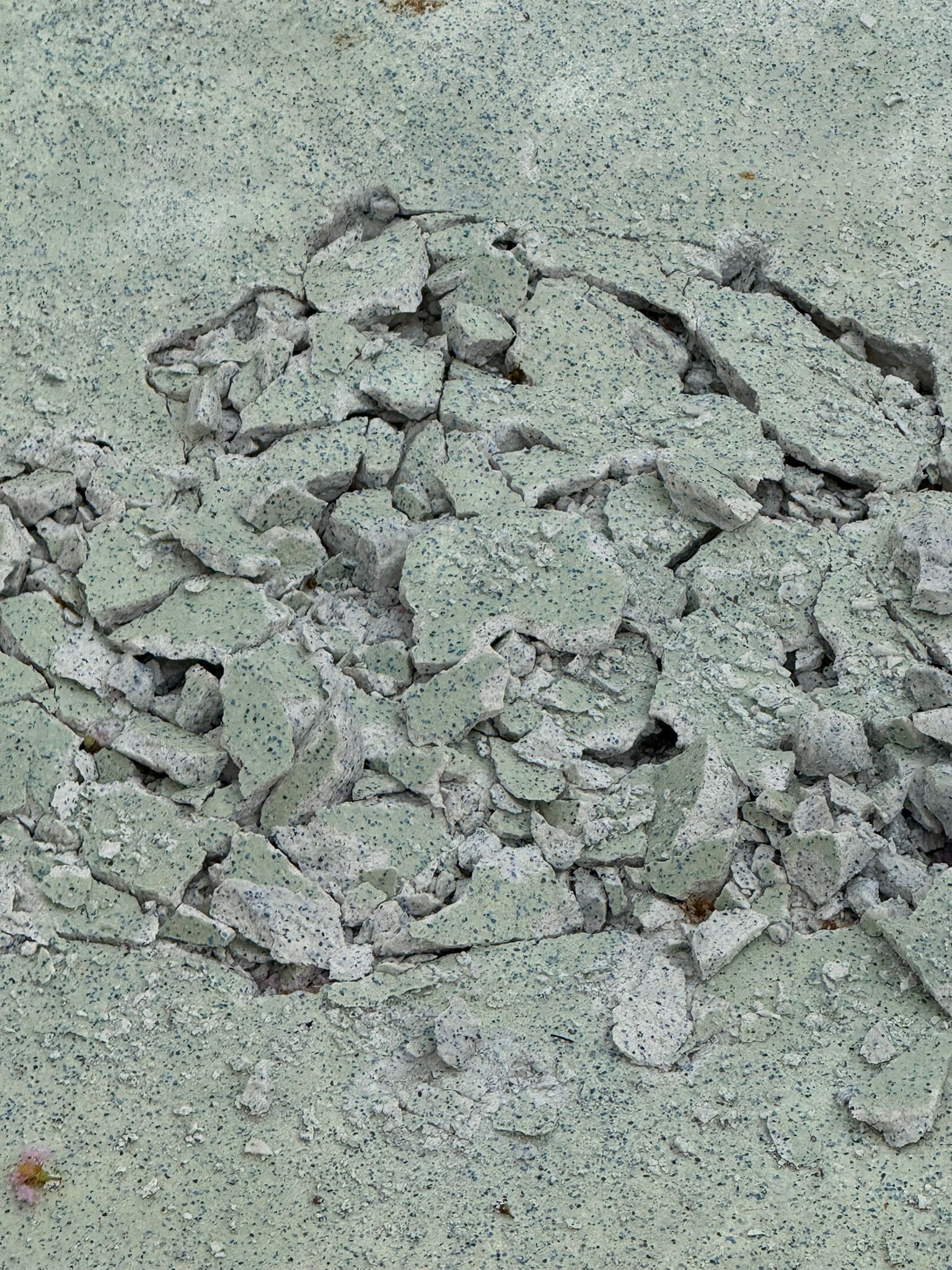 Cracked light green surface with chunks of broken material.