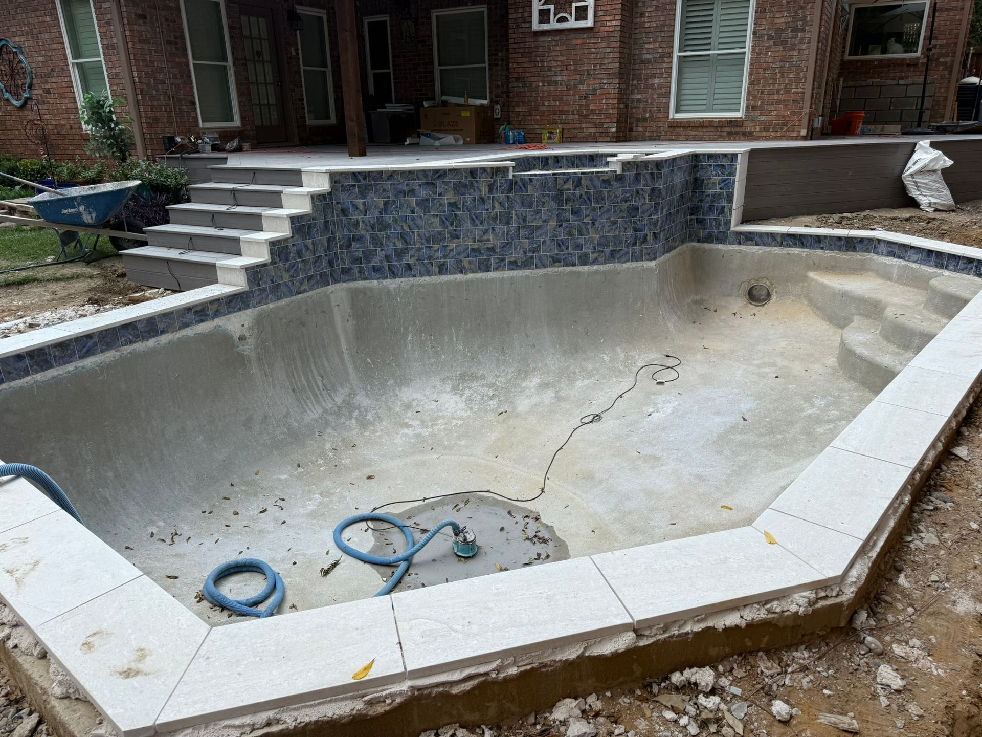 Empty swimming pool under construction, with new tile and coping.
