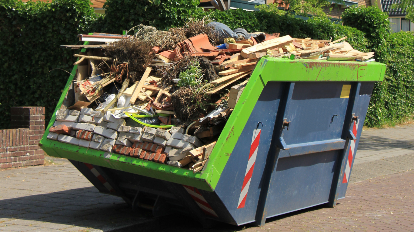 A dumpster filled with a lot of trash is parked on the side of the road.