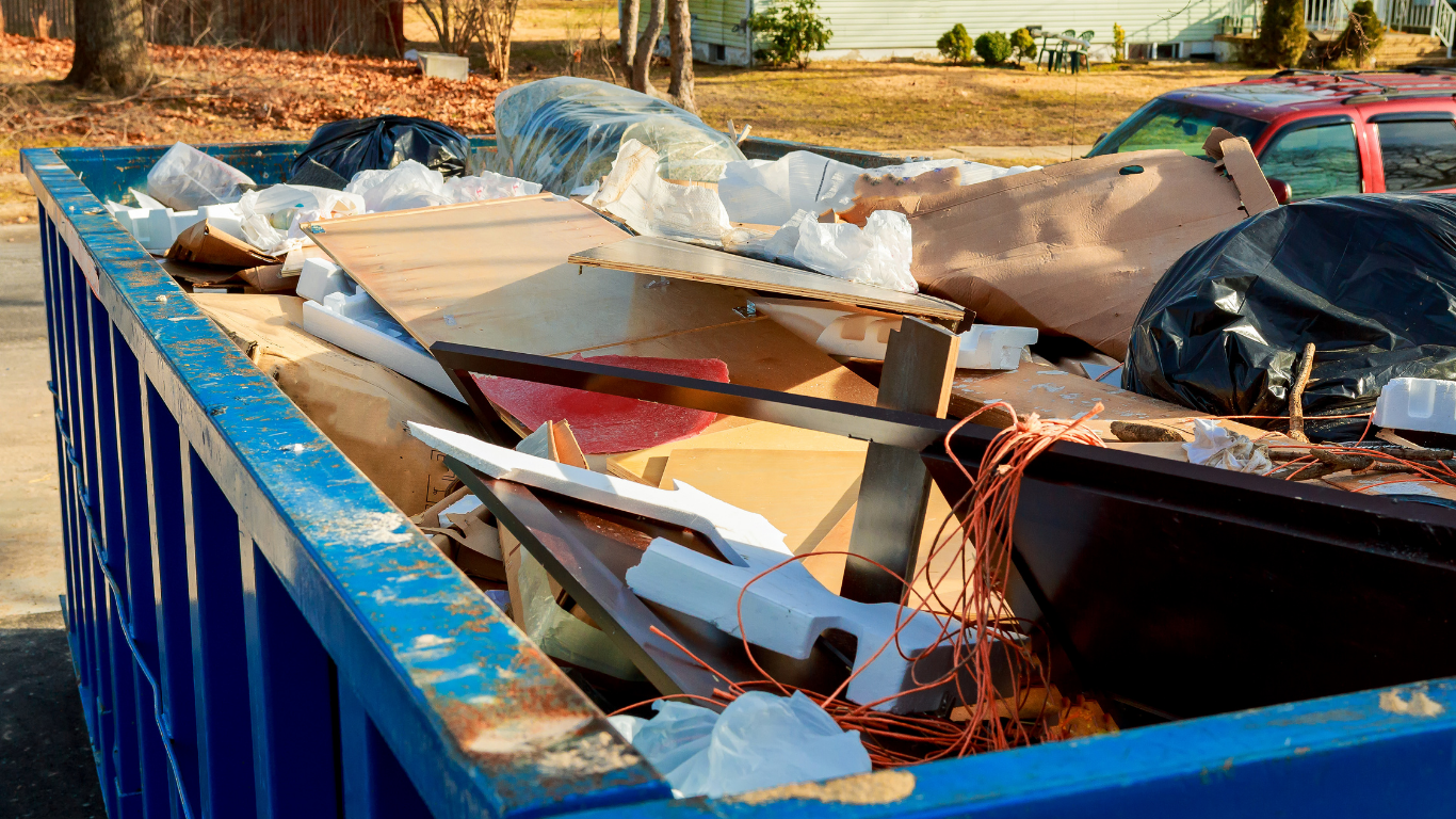 A blue dumpster filled with lots of garbage and trash.