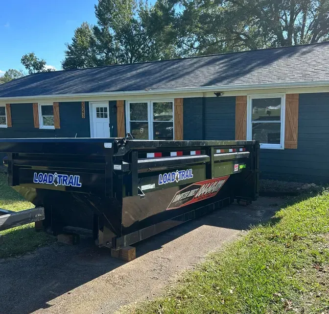 A dumpster is parked in front of a house.