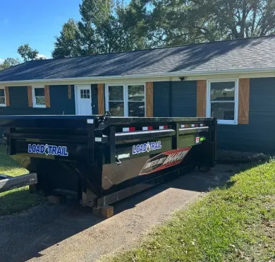 A dumpster is parked in front of a house.