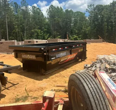 A trailer is sitting on top of a dirt field next to a tire.