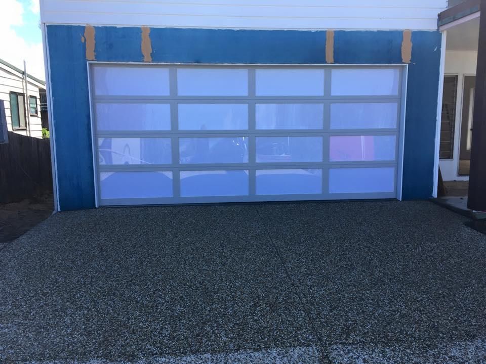 A White Garage Door is Sitting in Front of a House — P & D Garage Doors in Taree, NSW