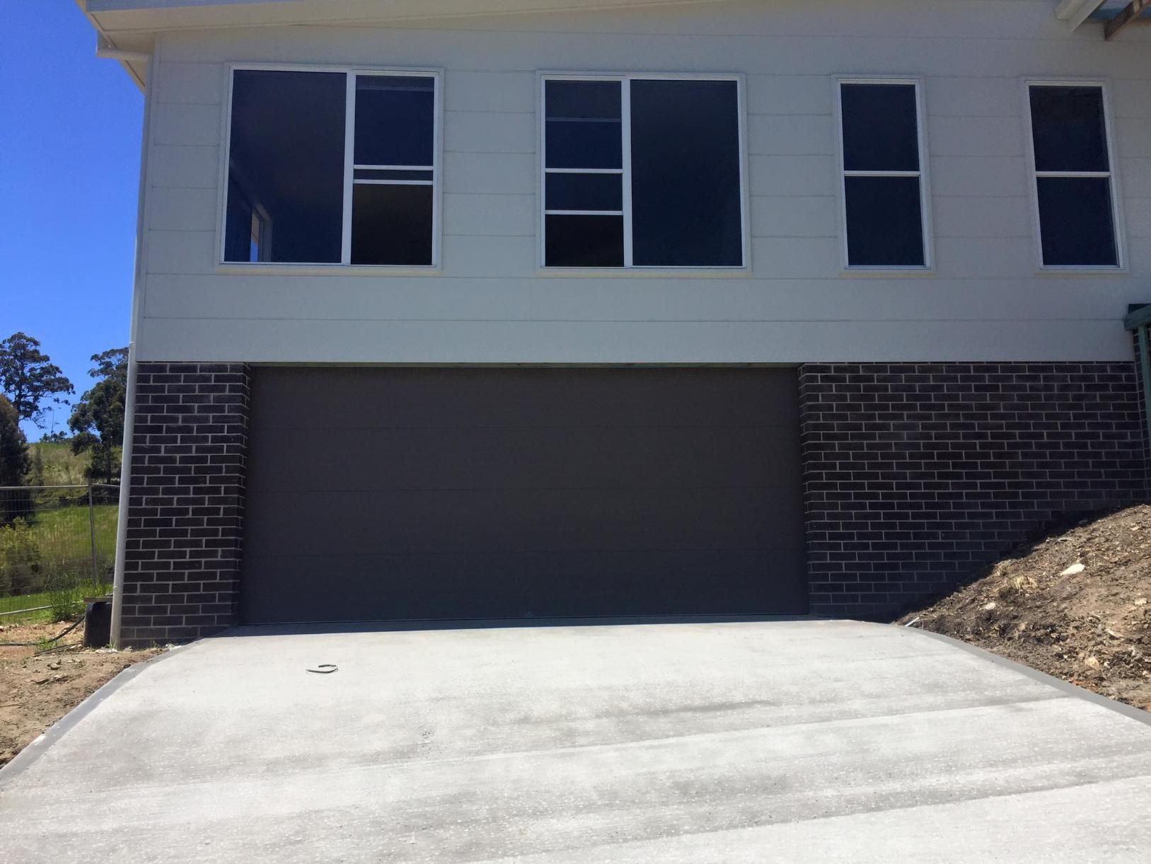 A Large White House With a Garage and a Driveway — P & D Garage Doors in Taree, NSW