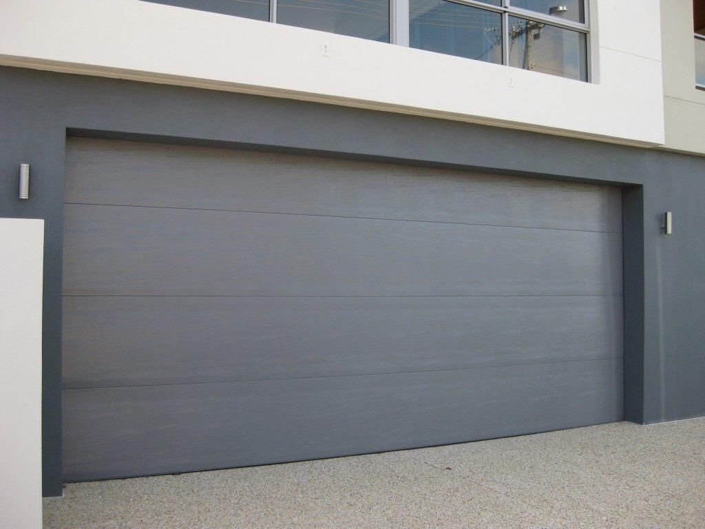 A Gray Garage Door is on the Side of a Building — P & D Garage Doors in Taree, NSW