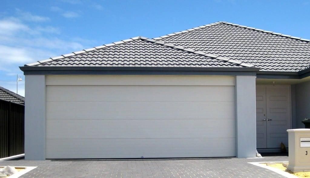 A white garage door in front of a house — P & D Garage Doors in Taree, NSW