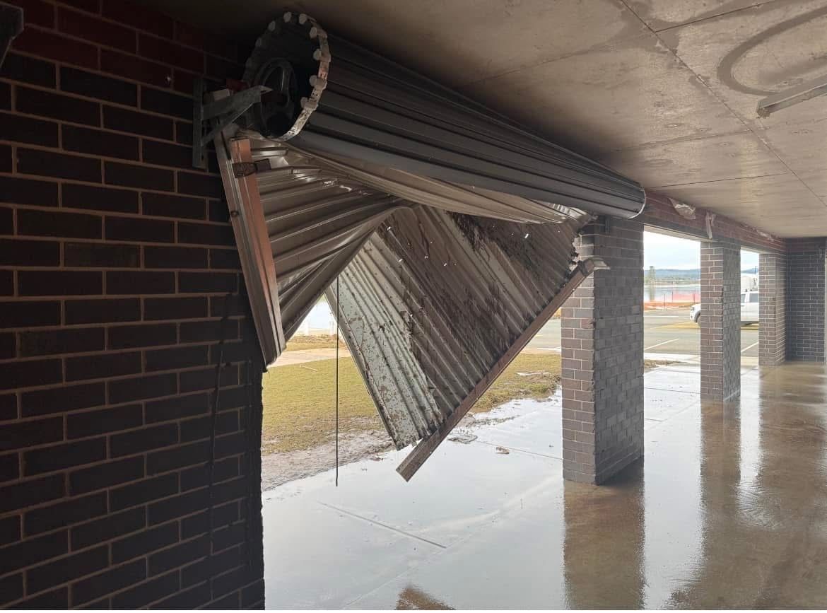 A brick building with a broken garage door. — P & D Garage Doors in Taree, NSW
