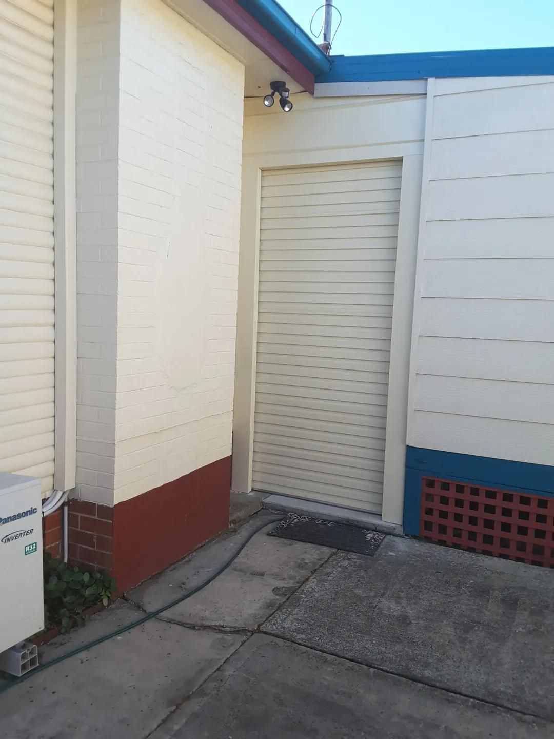 A white building with a hose attached to it — P & D Garage Doors in Taree, NSW