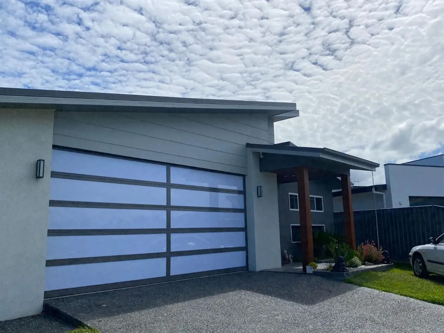 A car is parked in front of a house with a garage door. — P & D Garage Doors in Taree, NSW