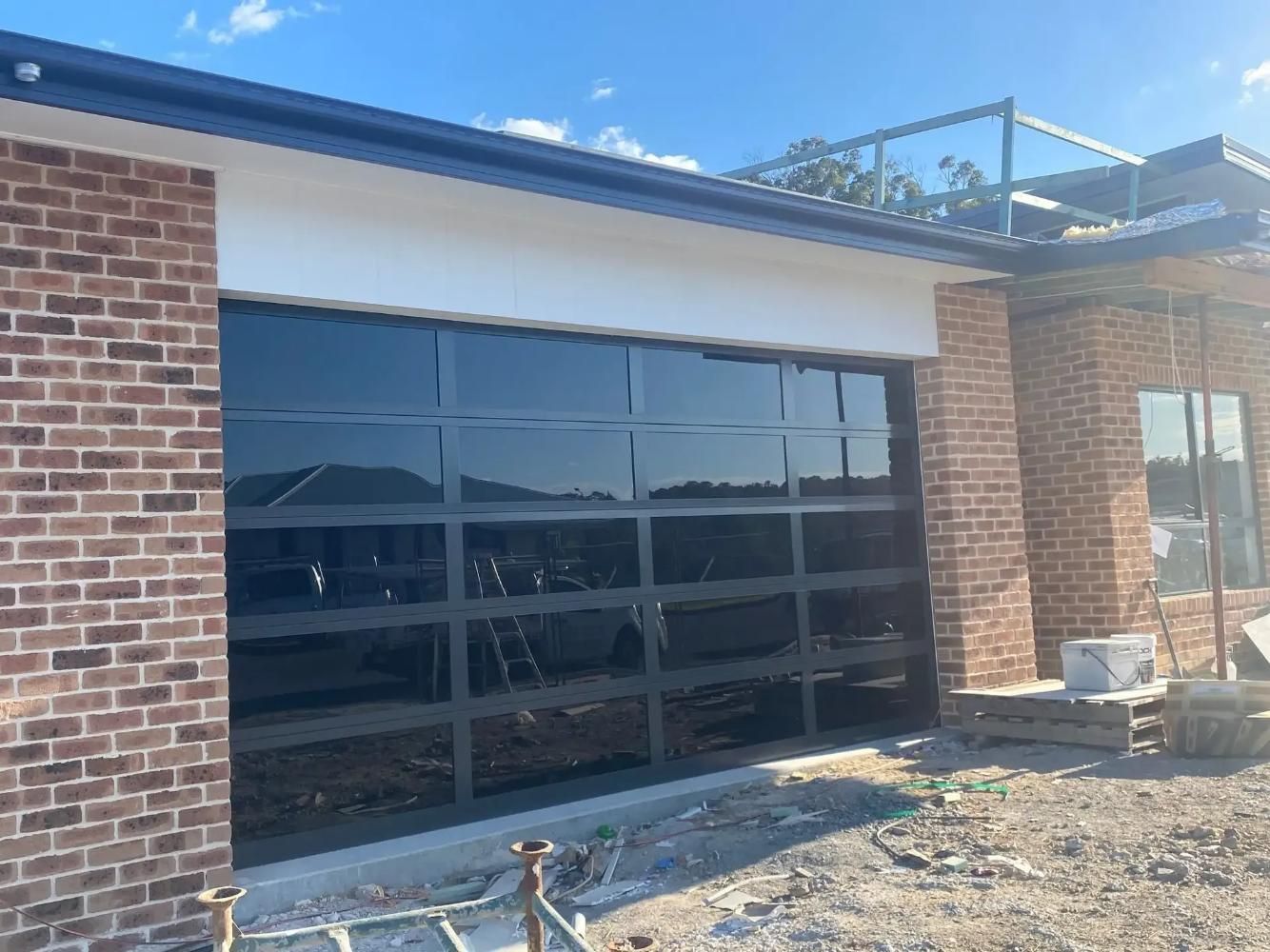 A brick house with a glass garage door is being built. — P & D Garage Doors in Taree, NSW
