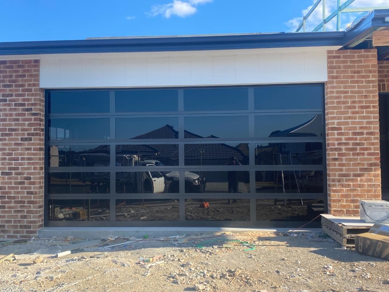 A Garage Door With a Lot of Windows is Sitting in Front of a Brick Building — P & D Garage Doors in Taree, NSW