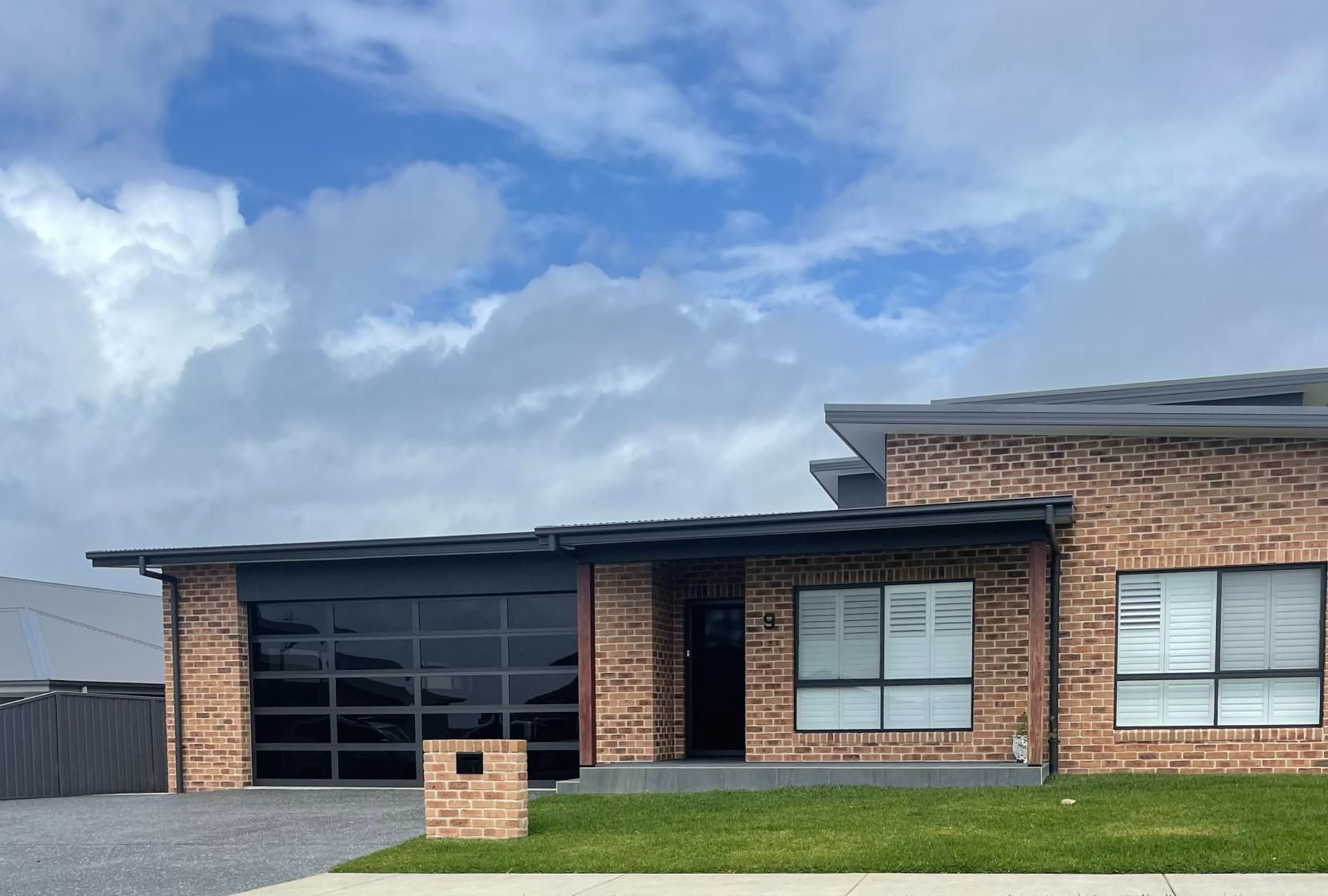 A Large Brick House With a Large Garage Door — P & D Garage Doors in Taree, NSW