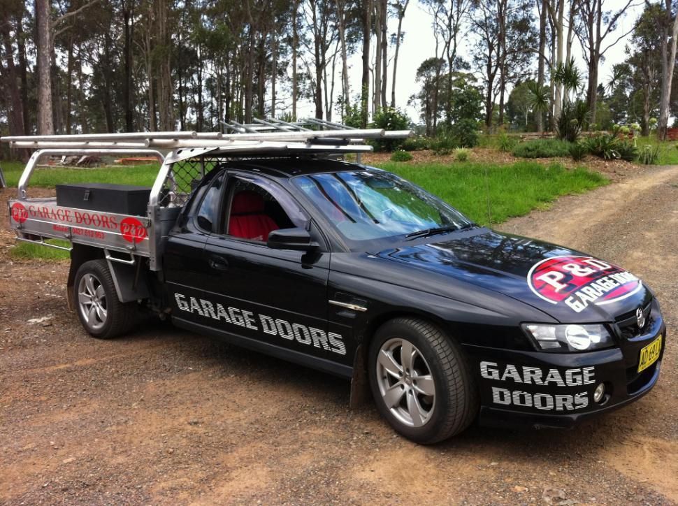 A Black Garage Doors Truck is Parked on a Dirt Road — P & D Garage Doors in Taree, NSW