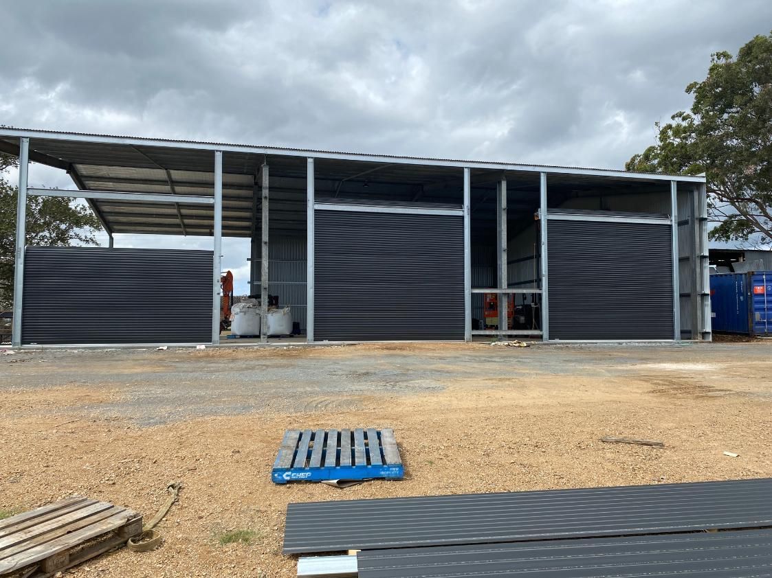 A Large Building is Being Built in a Dirt Field — P & D Garage Doors in Taree, NSW