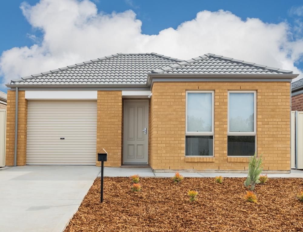 A Small Brick House With a White Garage Door — P & D Garage Doors in Pacific Palms, NSW