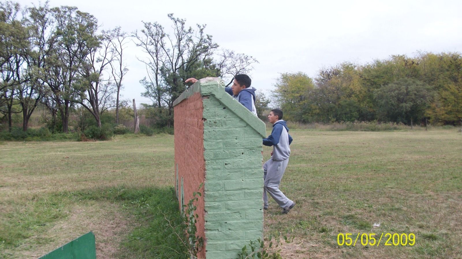 Dos personas escalando un colorido muro al aire libre en un campo de hierba.